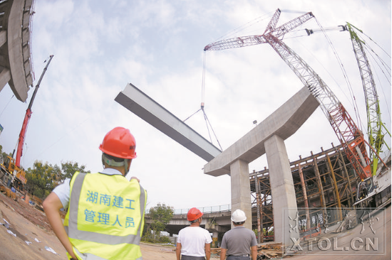 紅易-滬昆跨線(xiàn)橋跨滬昆高速公路主跨架梁施工現(xiàn)場(chǎng)，一節(jié)節(jié)鋼箱梁被吊起安裝。（記者 方陽(yáng) 攝）